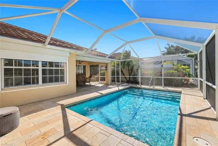 View of pool featuring a sunroom, glass enclosure, and patio surround