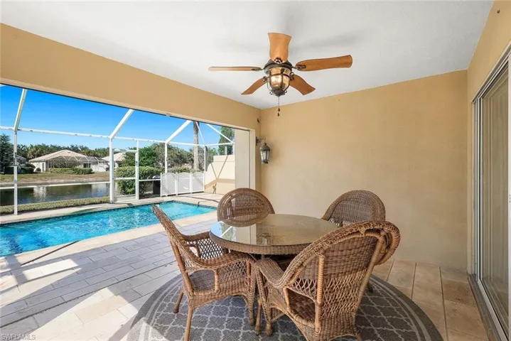 Swimming pool with a sunroom, glass enclosure, a patio, outdoor dining area, and a water view