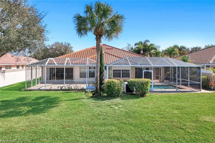 Back of house with glass enclosure, a sunroom, and a tile roof