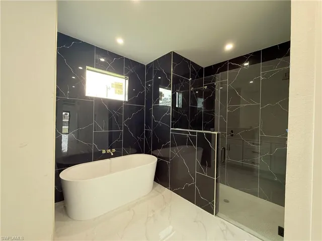 Bathroom featuring tile walls and independent shower and bath