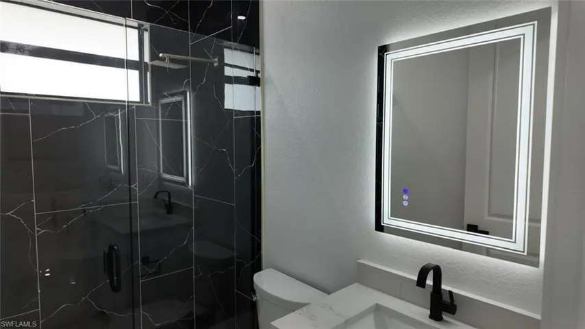Bathroom with toilet, a shower with door, and vanity