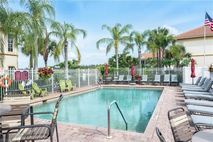 Community pool with a brick paver deck and surrounded by palm trees