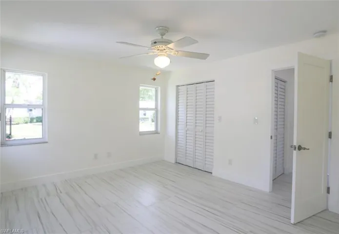 Unfurnished bedroom with ceiling fan and multiple windows