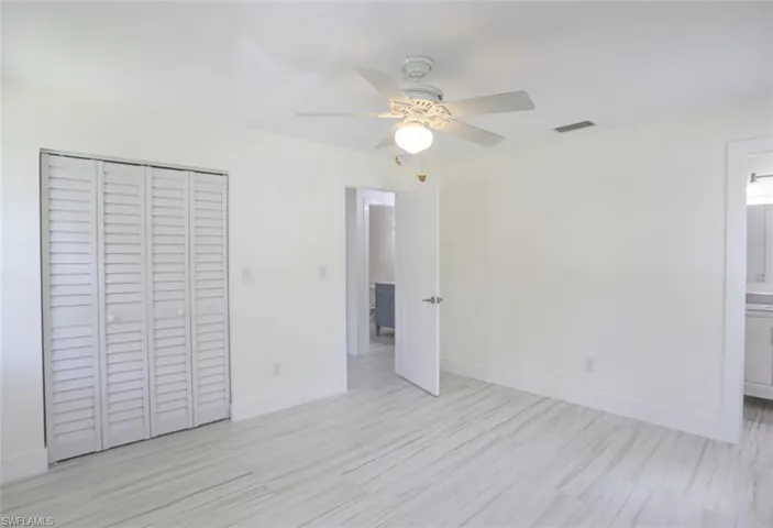 Unfurnished bedroom featuring a closet, connected bathroom, and ceiling fan