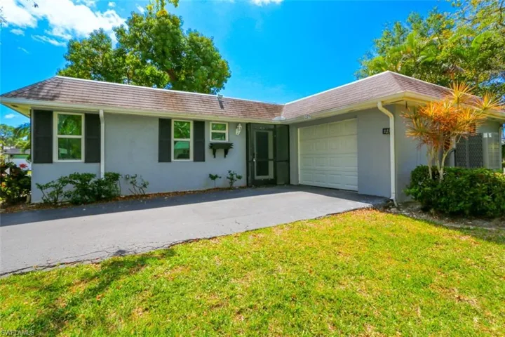 Single story home with a garage and a front lawn