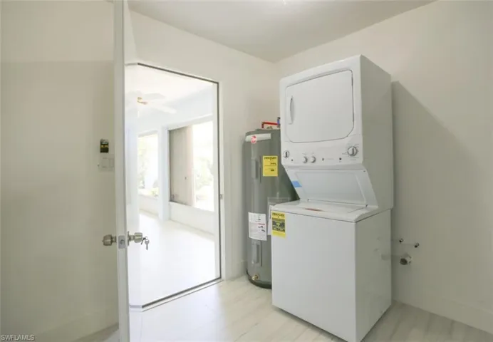 Clothes washing area featuring electric water heater and stacked washer and dryer