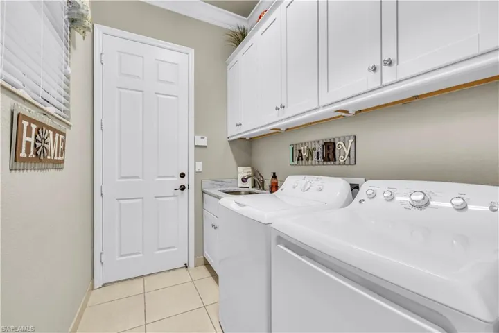 Laundry room with added cabinet for storage and laundry sink.