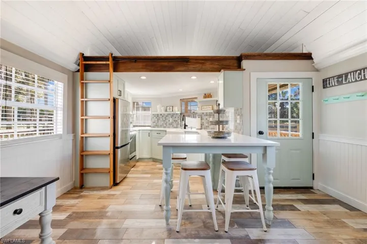 Kitchen featuring a breakfast bar, white cabinetry, stainless steel fridge, backsplash, and kitchen peninsula