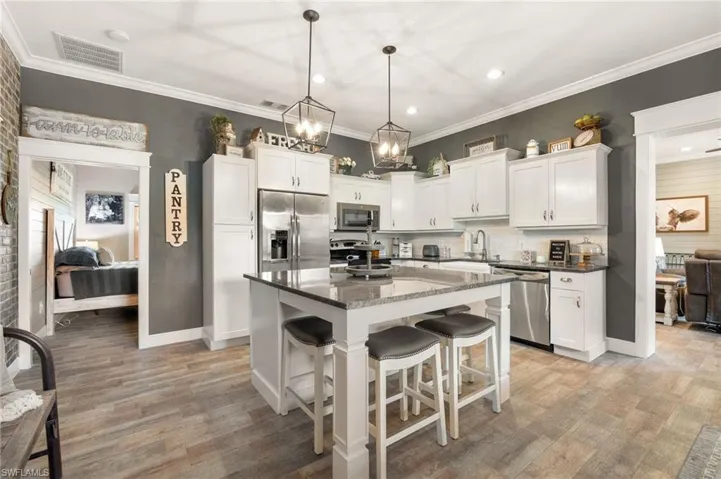 Kitchen with a kitchen bar, decorative light fixtures, a center island, stainless steel appliances, and white cabinets