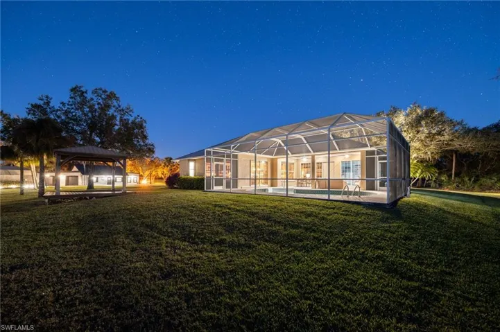 Rear view of house with a gazebo, a lanai, and a lawn
