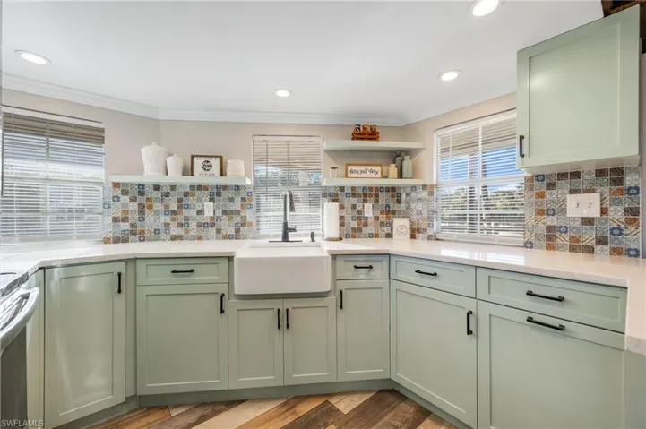 Kitchen featuring sink, crown molding, stove, hardwood / wood-style floors, and green cabinetry