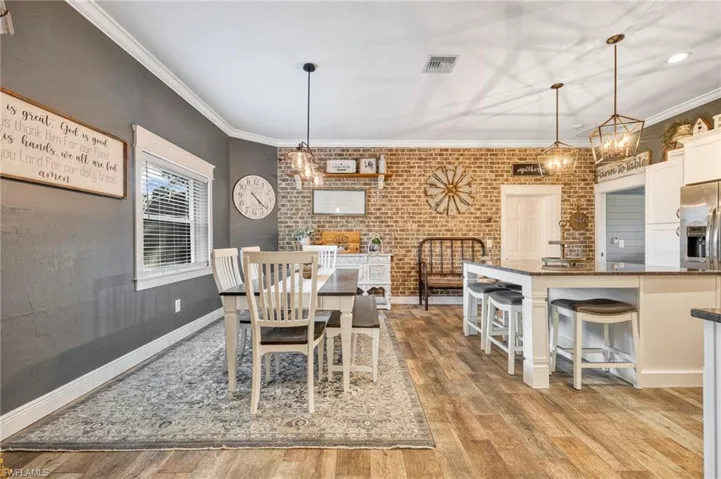 Dining space featuring crown molding, brick wall, and light hardwood / wood-style floors