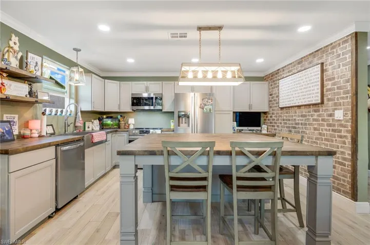 Kitchen featuring pendant lighting, stainless steel appliances, wooden counters, and a center island