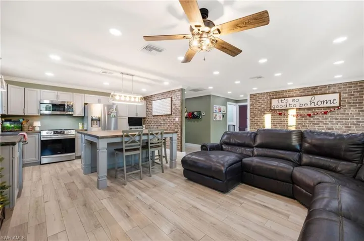 Living room featuring crown molding, light wood-type flooring, and brick wall