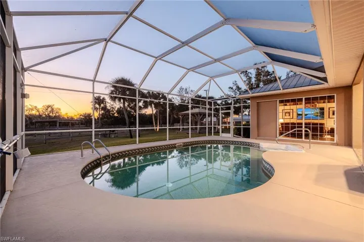 Pool at dusk with a lanai and a patio area
