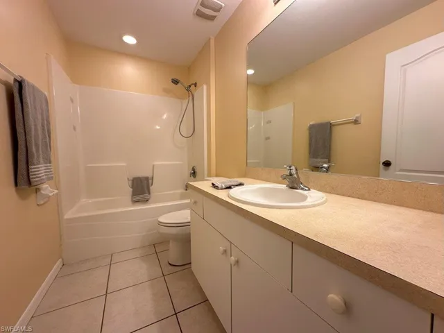 Full bathroom featuring tub / shower combination, vanity, tile patterned flooring, and toilet