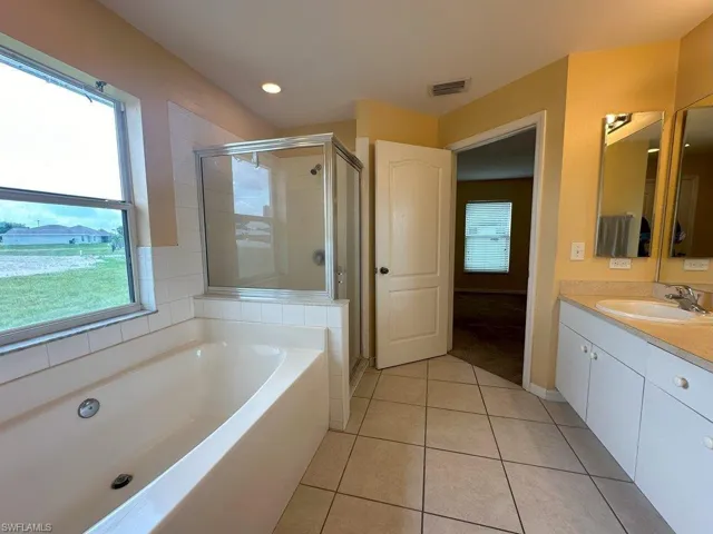 Bathroom with independent shower and bath, plenty of natural light, vanity, and tile patterned floors