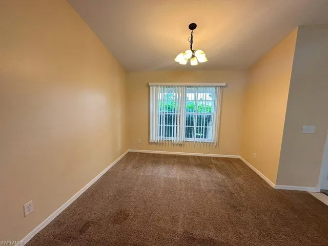 Unfurnished Dining Area with a notable chandelier, vaulted ceiling, and carpet floors