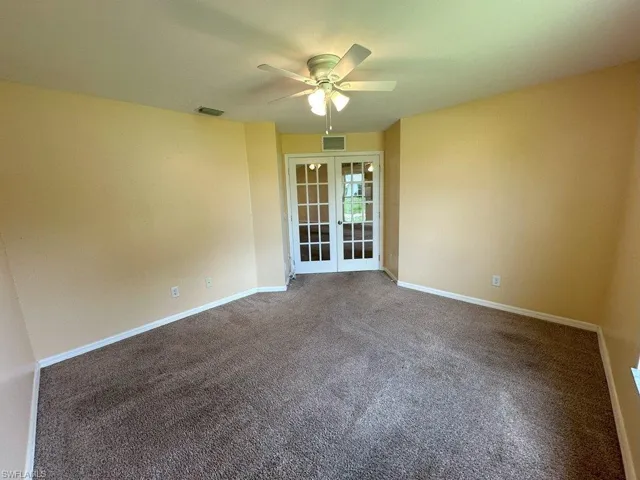 Den with ceiling fan, french doors, and carpet