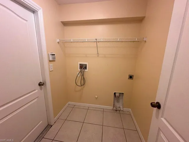 Clothes washing area featuring hookup for an electric dryer, light tile patterned floors, hookup for a gas dryer, and washer hookup