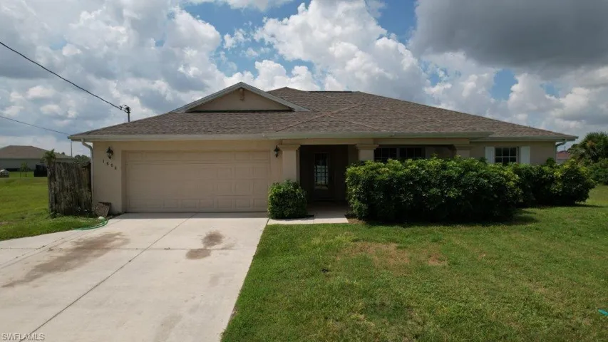 Ranch-style house with a garage and a front lawn