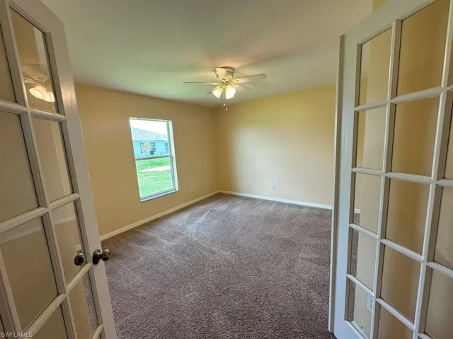 Den with ceiling fan and carpet floors