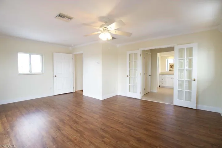 Spare room featuring french doors, dark wood finished floors, ornamental molding, and a ceiling fan