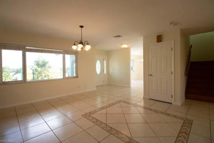 Tiled empty room with plenty of natural light, high vaulted ceiling, and ceiling fan