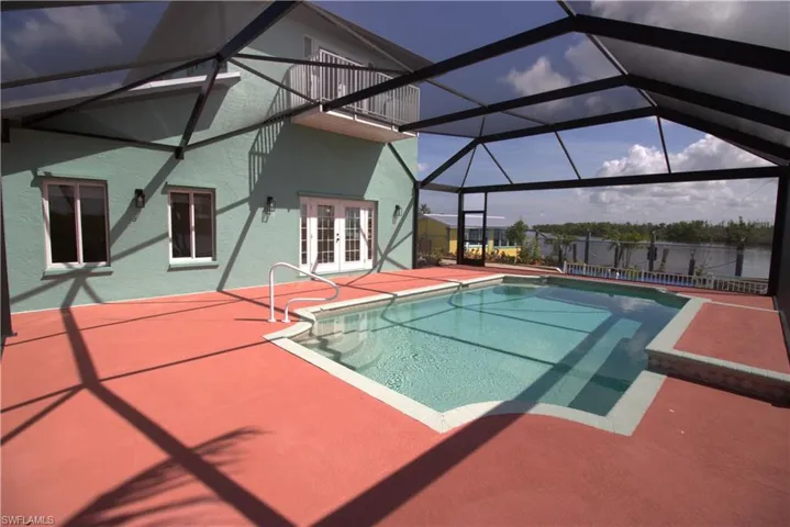 Swimming pool with a patio area, a lanai, a sunroom, and french doors