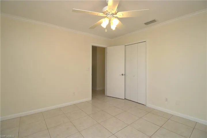 Unfurnished room featuring ornamental molding, light tile patterned flooring, and ceiling fan