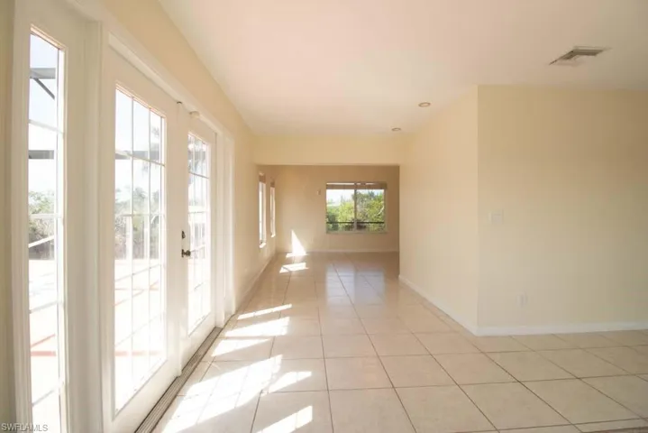 Unfurnished dining area with light tile patterned floors, french doors, inlaid floor details, and a chandelier