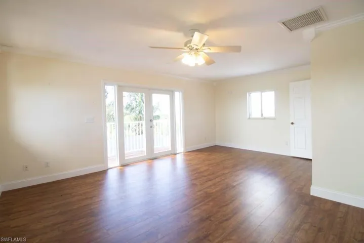 Unfurnished room with dark wood-type flooring, crown molding, a ceiling fan, and french doors