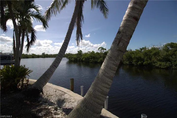Dock area featuring boat lift, a sunroom, and a deck with water view