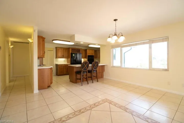 Kitchen with brown cabinets, black appliances, light tile patterned floors, and recessed lighting