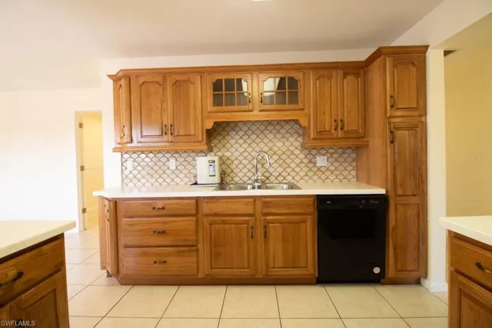 Kitchen featuring decorative backsplash, brown cabinetry, dishwasher, and light tile patterned floors