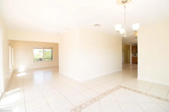 Kitchen with brown cabinets, black appliances, light tile patterned floors, light stone counters, and decorative backsplash