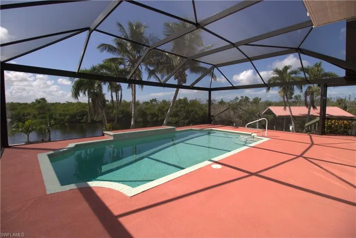 Outdoor pool with a hot tub, glass enclosure, and a sunroom