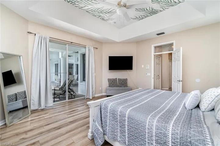 Bedroom with a raised ceiling, wood finished floors, and access to exterior