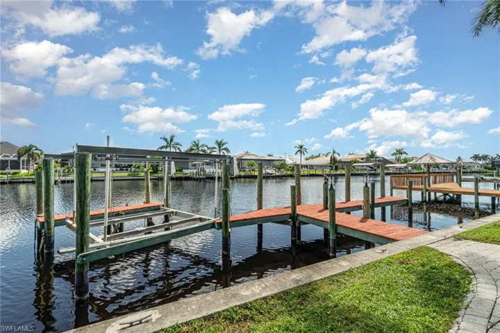 Dock with boat lift, a water view, and a residential view