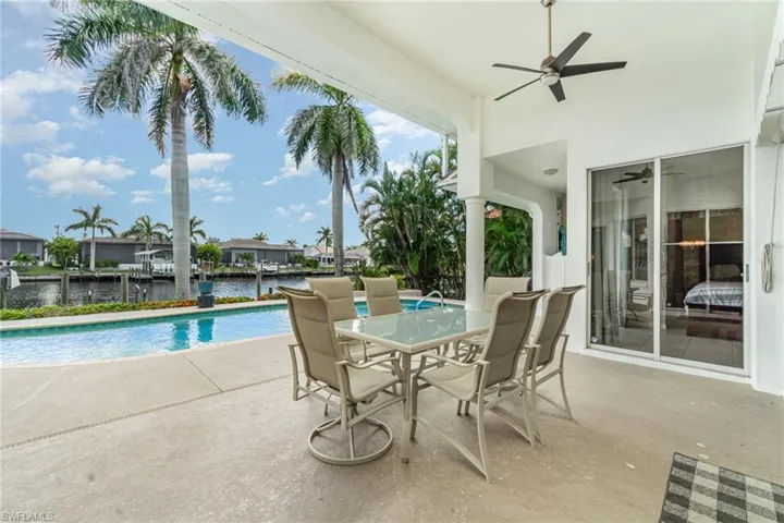 Swimming pool featuring a patio area, a water view, outdoor dining space, and a ceiling fan