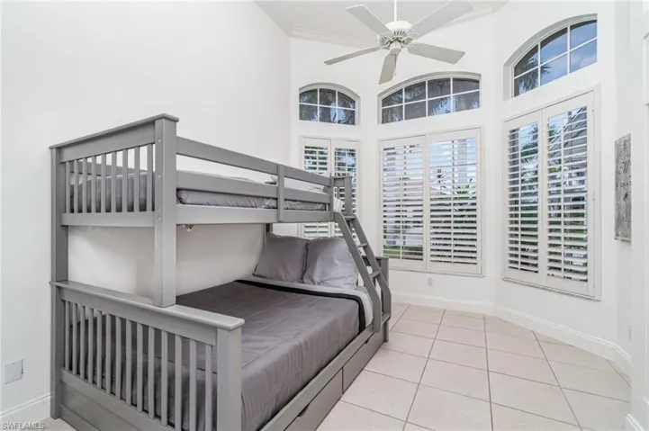 Bedroom featuring light tile patterned floors, ceiling fan, and a high ceiling