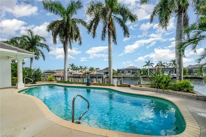 Outdoor pool featuring a water view, a patio, a residential view, a boat dock, and boat lift