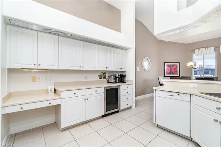 Kitchen featuring white dishwasher, white cabinets, beverage cooler, and light tile patterned flooring
