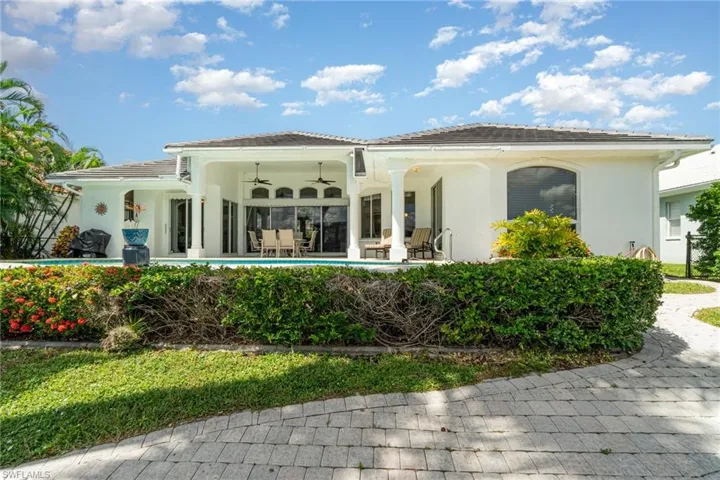 Rear view of house featuring a ceiling fan, stucco siding, a tile roof, and a patio area