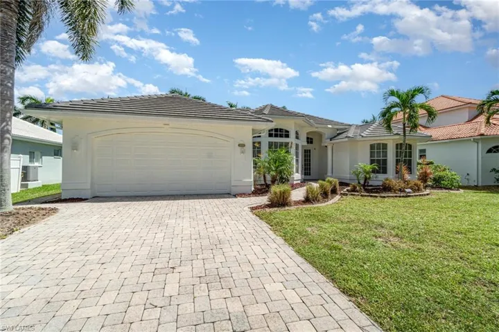 View of front of property with a tiled roof, a front lawn, decorative driveway, and a garage