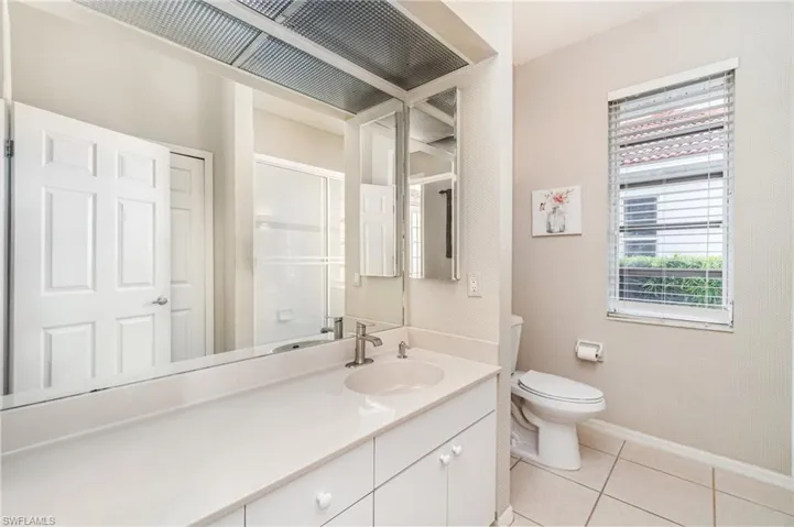 Bathroom with vanity, light tile patterned flooring, and a shower with door