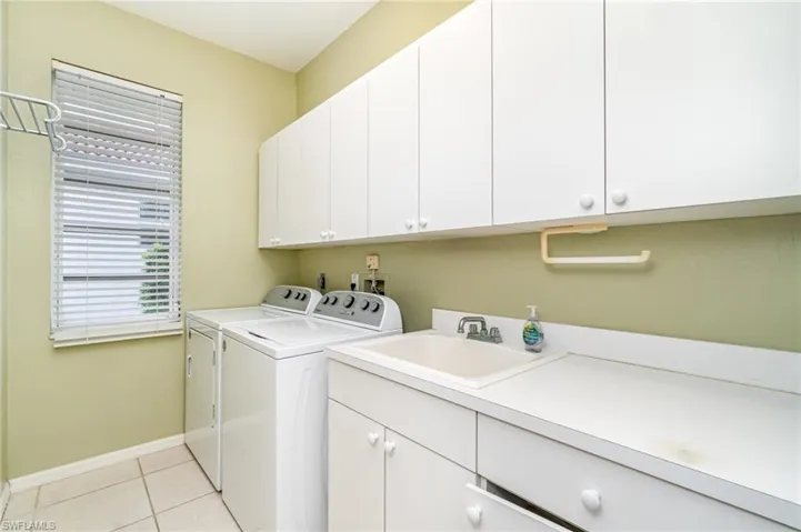 Washroom featuring cabinet space, light tile patterned floors, and washer and clothes dryer