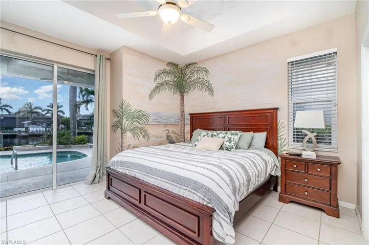 Bedroom featuring access to exterior, a raised ceiling, ceiling fan, and light tile patterned floors