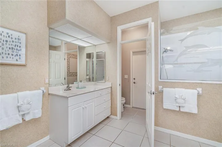Full bathroom featuring vanity, a shower stall, light tile patterned floors, and wallpapered walls