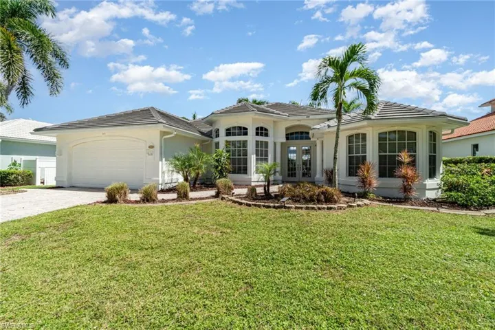 Mediterranean / spanish-style house with french doors, a front yard, a tiled roof, and an attached garage